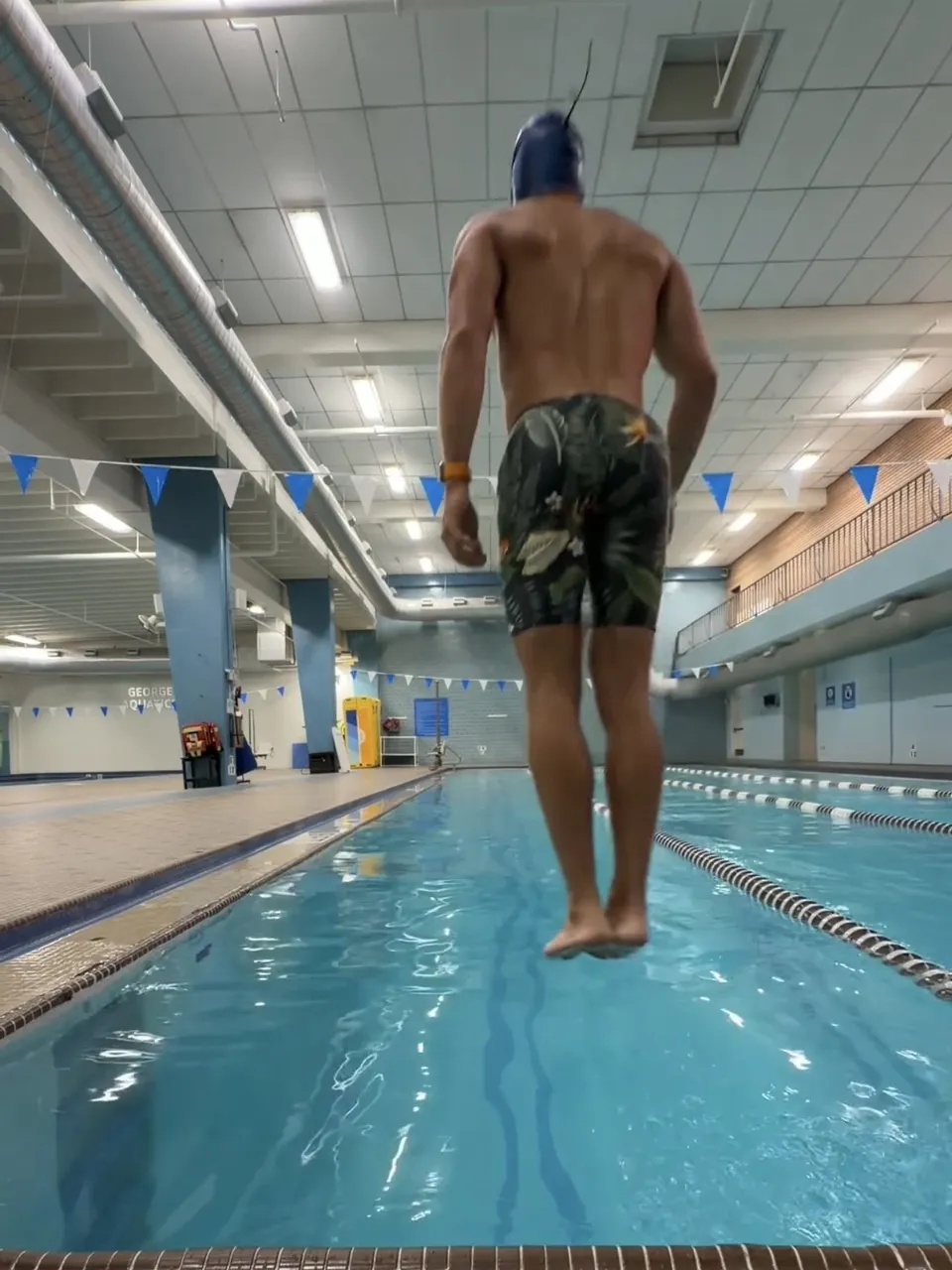 Thomas mid-jump into a lap pool, seen from behind